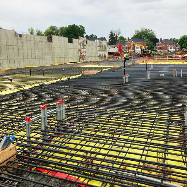Slab-on-grade rebar on the east side of the building. The south wall (from Photo #1) is on the left. Mechanical, electrical, and plumbing (MEP) piping penetrations are shown with the red tape on top. Slab-on-grade rebar on the east side of the building. The south wall (from Photo #1) is on the left. Mechanical, electrical, and plumbing (MEP) piping penetrations are shown with the red tape on top.